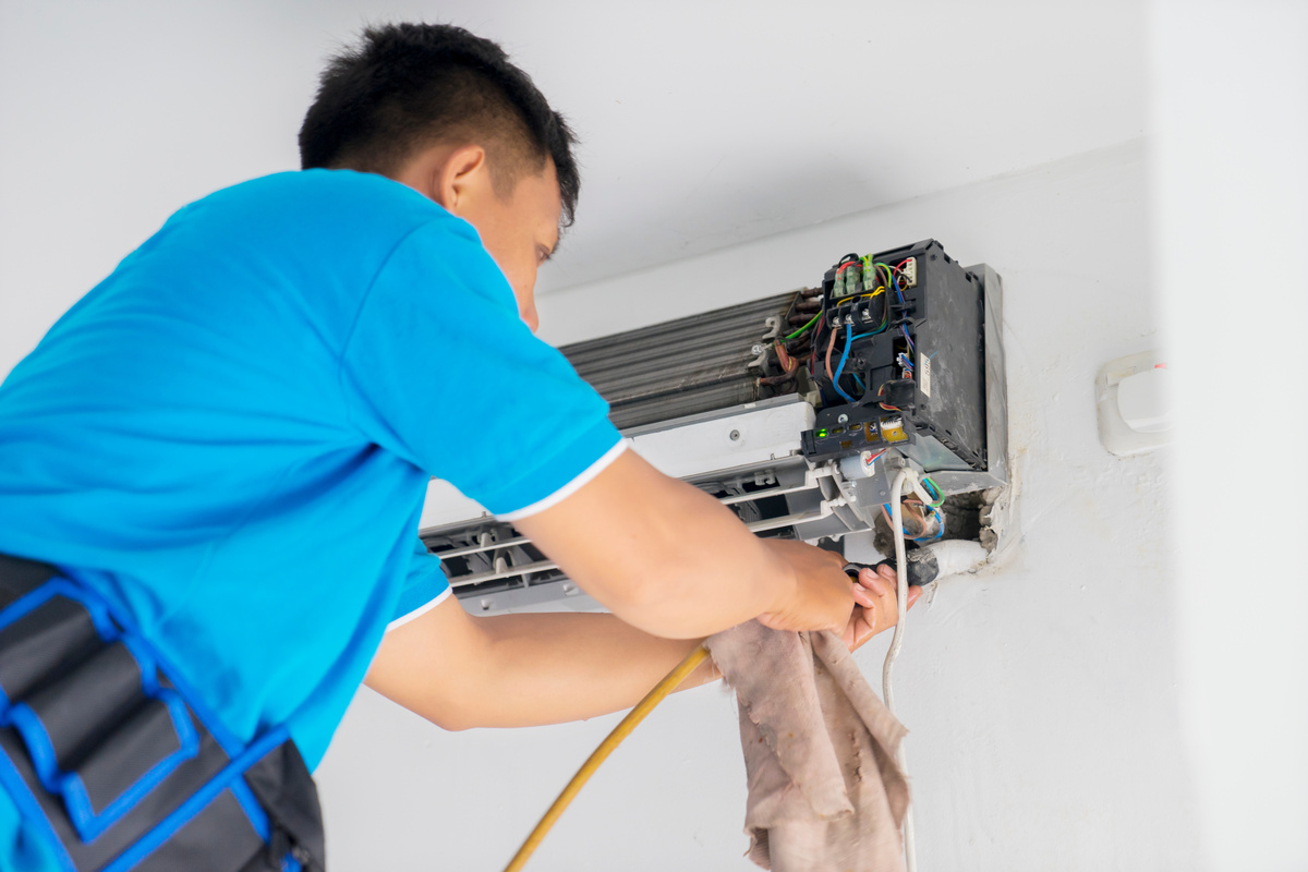 Picture of young male technician cleaning coil cooler of air conditioner, Shot at home